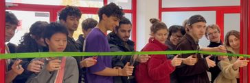 Students cut through a barrier tape together to open an exhibition