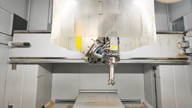 Detailansicht des Fräskopfes einer CNC-Maschine mit eingesetztem Werkzeug, umgeben von einer transparenten Schutzabdeckung im Innenraum der Maschine.