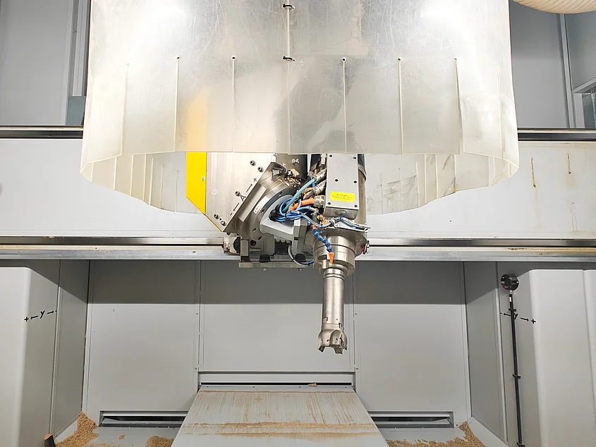 Detailansicht des Fräskopfes einer CNC-Maschine mit eingesetztem Werkzeug, umgeben von einer transparenten Schutzabdeckung im Innenraum der Maschine.