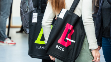 zwei Menschen von schräg hinten, die jeweils einen schwarzen Beutel der »Simply B«-Reihe über der Schulter tragen