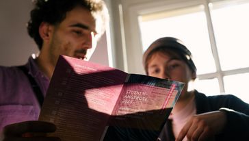 Zwei Personen schauen auf die gedruckte Studienübersicht