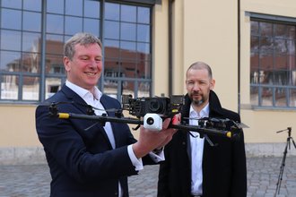 Prof. Dr. Guido Morgenthal (r.) demonstrierte dem Staatssekretär Carsten Feller (TMWWDG) mit einem Drohnenflug seine Forschung zu denkmalgerechter Sanierung historischer Bauwerke. (Foto: TMWWDG/C. Werner)
