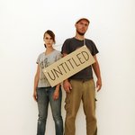 Photograph of the artist duo with a cardboard sign that reads »untitled«