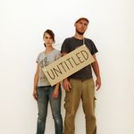 Fotografie des Künstlerduos mit einem Pappschild, auf dem »untitled« steht