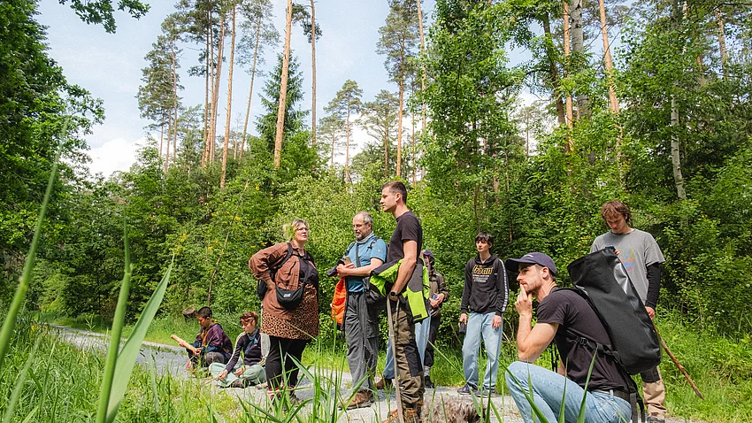 eine Gruppe Menschen des Projekts »PostCompst« bei ihrer Exkursion in den Wald
