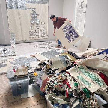 Jana Gunstheimer zwischen sehr vielen Textilen Arbeiten, eine hängt bereits hinter ihr an der Wand