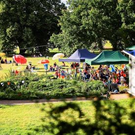 Szene vom Hörspielsommer: Wiese mit Zelten, bunten Schirmen und Menschen; Foto: Tino Pfund