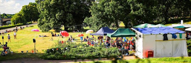 Scene from the radio play summer: Meadow with tents, colourful umbrellas and people; Photo: Tino Pfund
