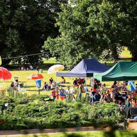 Scene from the radio play summer: Meadow with tents, colourful umbrellas and people; Photo: Tino Pfund