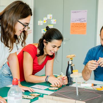 Three people tinker with a project.