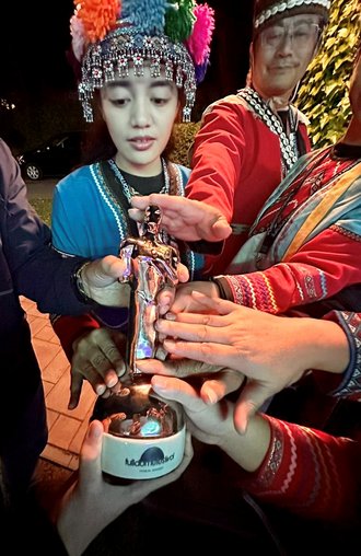 Taiwanesische Personen in traditionellen Gewändern berühren den Janus-Pokal.