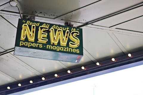 News inscription on a neon signboard hanging on street.