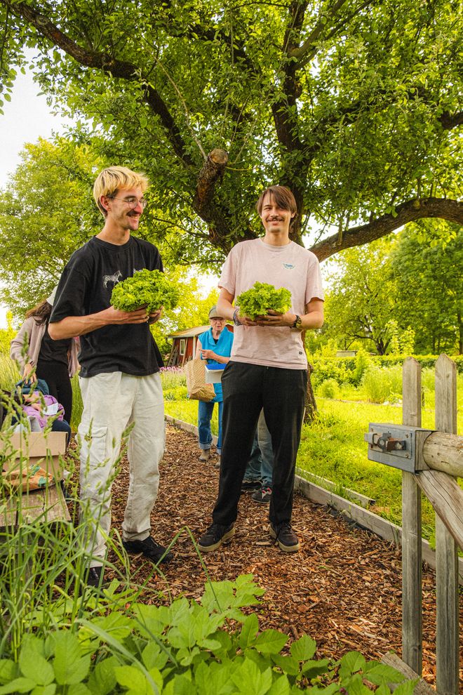 zwei Personen mit Salat in der Hand im Garten