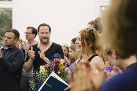 Foto der Preisträgerin mit Urkunde in einer Menschenmenge