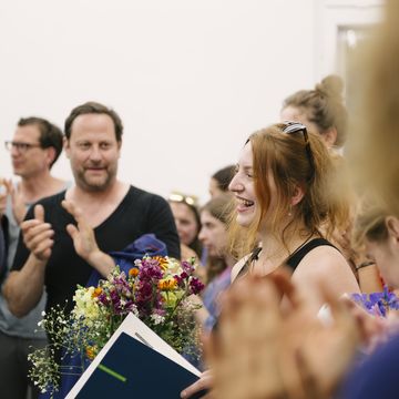Foto der Preisträgerin mit Urkunde in einer Menschenmenge