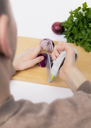 Eine Person mit Cook Ability Griff und Messeraufsatz zerschneidet Zwiebeln