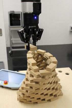 Foto eines Roboterams, der Steine stapelt