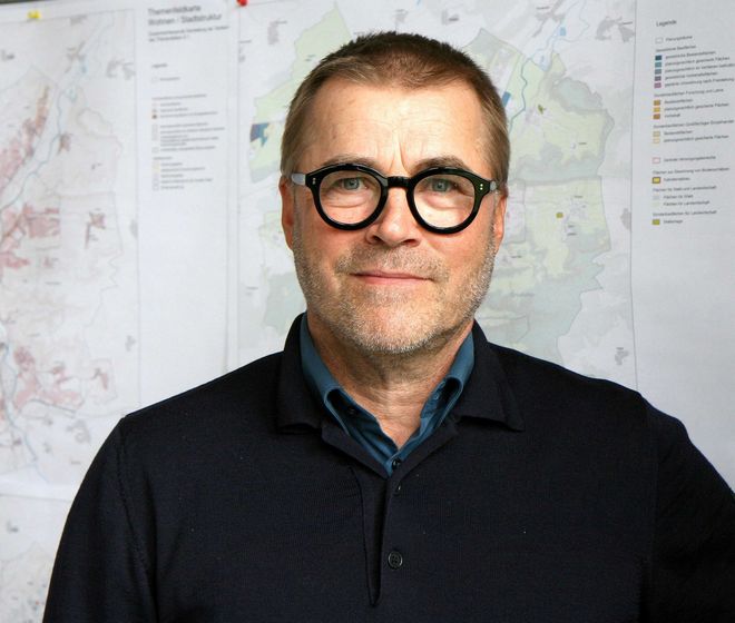 Porträt eines Mannes mit dunkler Brille und dunklem Pullover