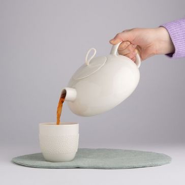 Teekanne füllt Tee in Tasse