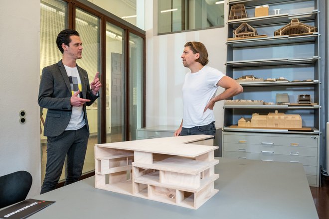 Liedermacher Philip Poisel und Moderator Jo Schück unterhalten sich vor einem Architekturmodel der Universitätsbibliothek. 