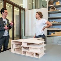 Liedermacher Philip Poisel und Moderator Jo Schück unterhalten sich vor einem Architekturmodel der Universitätsbibliothek. 