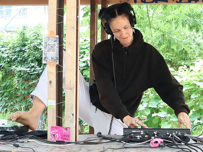 Person mit Kopfhörern bedient Audiotechnik beim »Flurfunk« zur summaery. Über dem improvisierten Sendestudio weisen Plakate auf die Frequenz 106,6 MHz und bauhaus.fm hin.