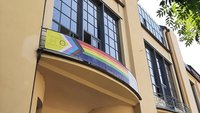 Das Foto zeigt ein Banner mit der »Inter*-inklusiven Progress-Pride-Flagge« am Hauptgebäude der Bauhaus-Universität Weimar.