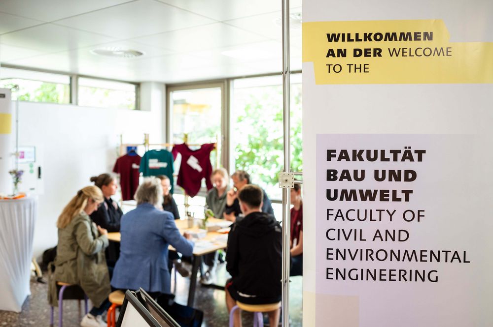 eine kleine Gruppe Menschen sitzt in der Mensa zusammen an einem Tisch