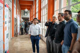 Juli 2019: Dr. Schwarz mit Studierenden des NHRE-Studiengangs während der Poster-Präsentation der »Special Projects« zur summaery 2019. (Foto: Thomas Müller) Juli 2019: Dr. Schwarz mit Studierenden des NHRE-Studiengangs während der Poster-Präsentation der »Special Projects« zur summaery 2019. Im Gespräch antwortet er den Studierenden des 3. und 4. Semesters auf ihre Fragen und gibt Hinweise an die Bearbeitenden. (Foto: Thomas Müller)