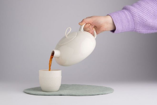 Teekanne füllt Tee in Tasse