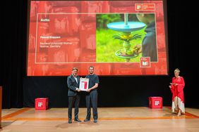 Pascal Stappen mit einem weiteren Mann auf einer sehr großen Bühne mit einer Urkunde in der Hand