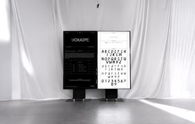 Exhibition view of »VOXAIPE – Decoded«, Photo: Mai Do Exhibition view of »VOXAIPE – Decoded« by Mai Do: two monitors stand in front of a light curtain. The left monitor explains the project, while the right monitor shows a voice-generated alphabet with handwritten-looking letterforms.