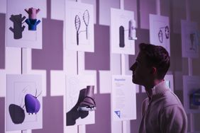 Besucher der Winterwerkschau vor einer Wand mit kleineren 3-D-gedruckten Objekten
