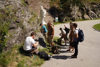 Studierende auf Exkursion an einem Felsen schauen sich Flechten genauer an