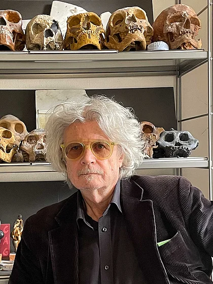 Portrait of Norbert Hinterberger in front of shelves displaying numerous skull models and small figurines.