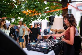 Tanzende Menschen und eine Frau am DJ-Pult