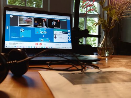 Schreibtisch mit Monitor auf dem eine Videokonferenz läuft