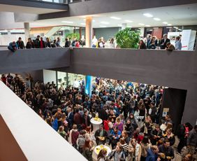 young people are standing in the foyer of the University Library, and there is a lively atmosphere