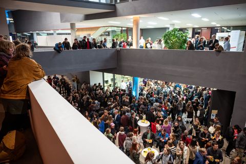 Herzlich Willkommen, liebe Erstsemester! young people are standing in the foyer of the University Library, and there is a lively atmosphere
