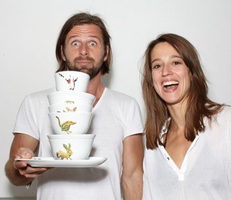 Fotografie von Laura Straßer und Kai Meinig, die lachend das von ihnen gestaltete Geschirr in den Händen halten.
