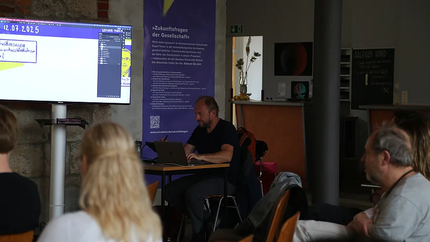 Illustrator Matthias Seifert zeichnet live bei der Podiumsdiskussion mit, das Publikum kann über einen großen Monitor verfolgen, was er gerade zeichnet