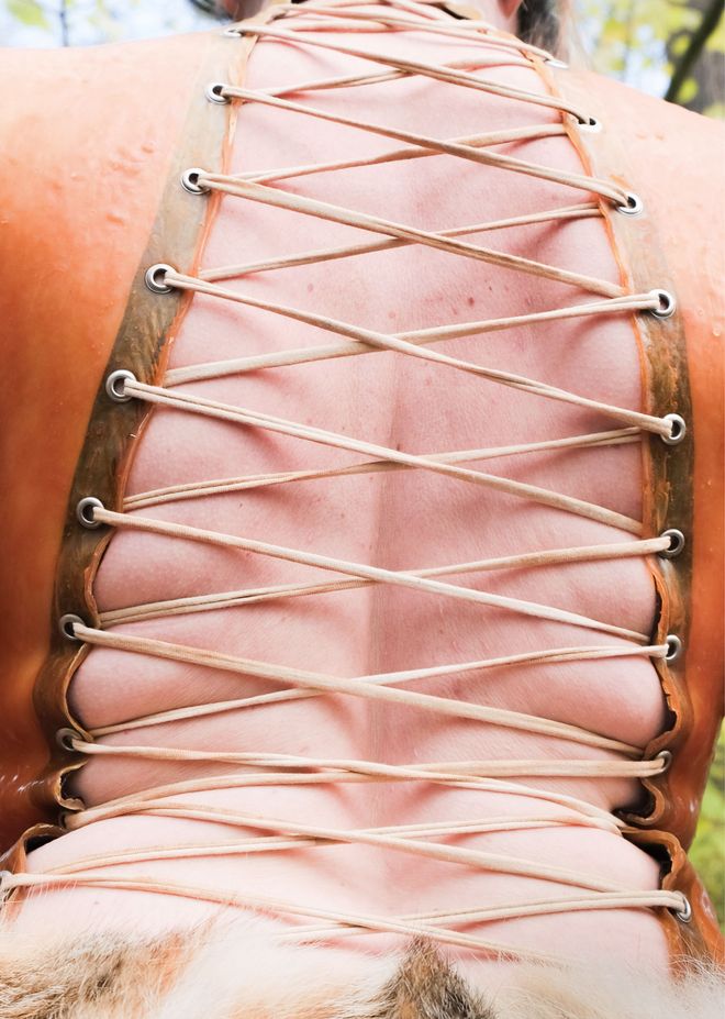 Close-up of a back in a tightly laced garment. The lacing crosses over the skin.