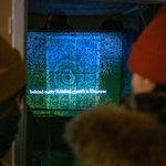 Impression der Winterwerkschau 2020: zwei Personen betrachten eine Projektion im Freien; Foto Thomas Müller
