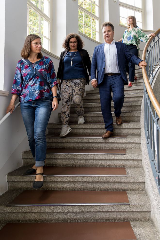 Christiane Hempel, Michaela Albrecht, Jürgen Dusel und Franziska Schönberner steigen die Wendeltreppe im Hauptgebäude hinab. Das Treppenhaus wurde von Henry van de Velde entworfen.