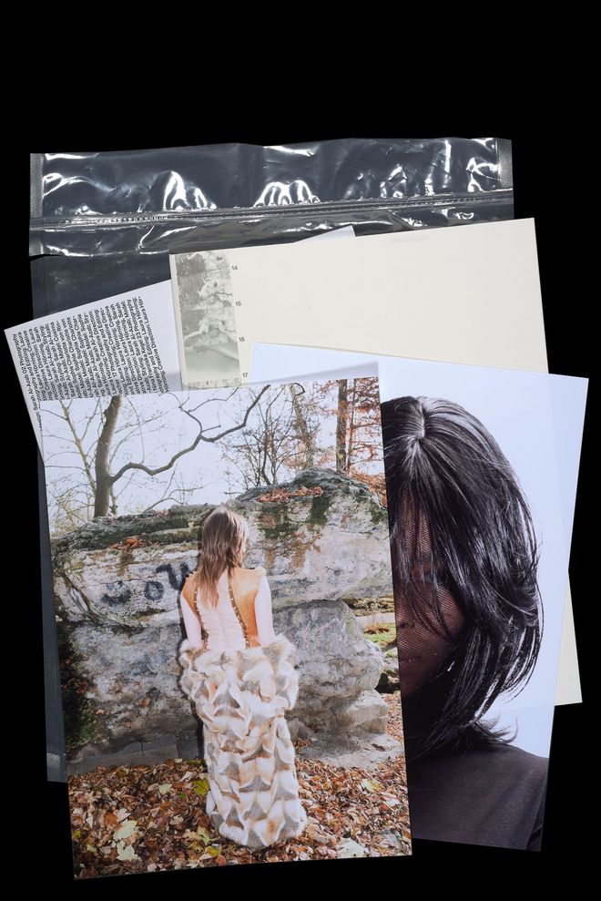 Still life with several printed magazine pages and photographs against a black background. Visible elements include a photograph of a person in front of rocks, a portrait with dark hair and a silver plastic sleeve.