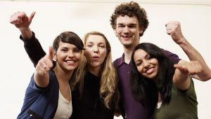 Vier lachende  und sich in den Armen liegende Internationale Studierende.