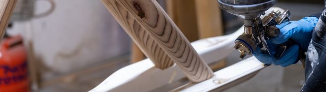 Close-up of wooden parts of a designed object with a spray gun for painting