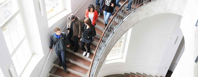 Eine Menschengruppe läuft im Hauptgebäude der Bauhaus-Universität Weimar die Treppe hoch.