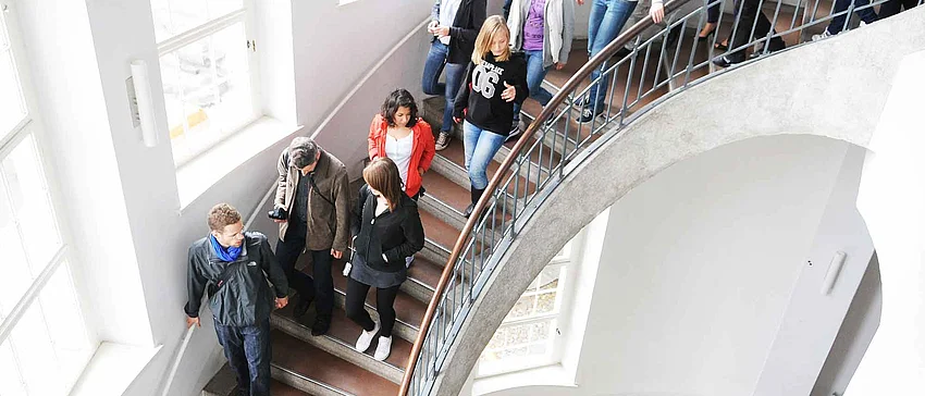 Eine Menschengruppe läuft im Hauptgebäude der Bauhaus-Universität Weimar die Treppe hoch.