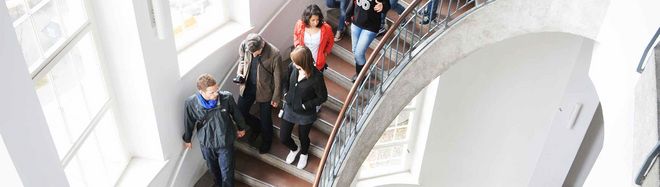 Eine Menschengruppe läuft im Hauptgebäude der Bauhaus-Universität Weimar die Treppe hoch.